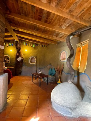 Un interior rústic amb bigues de fusta, una banca de pedra i un disseny de paret únic.