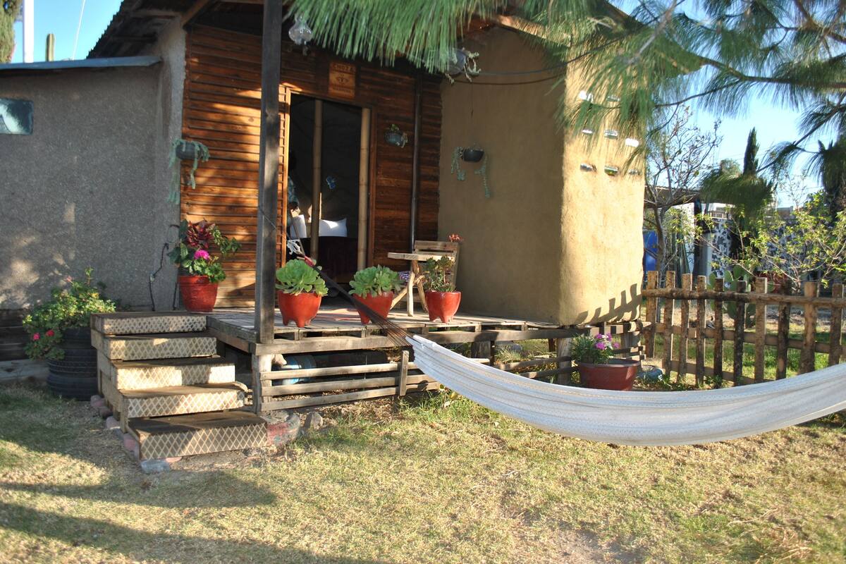 A wooden cabin with a porch, steps, and a hammock.
