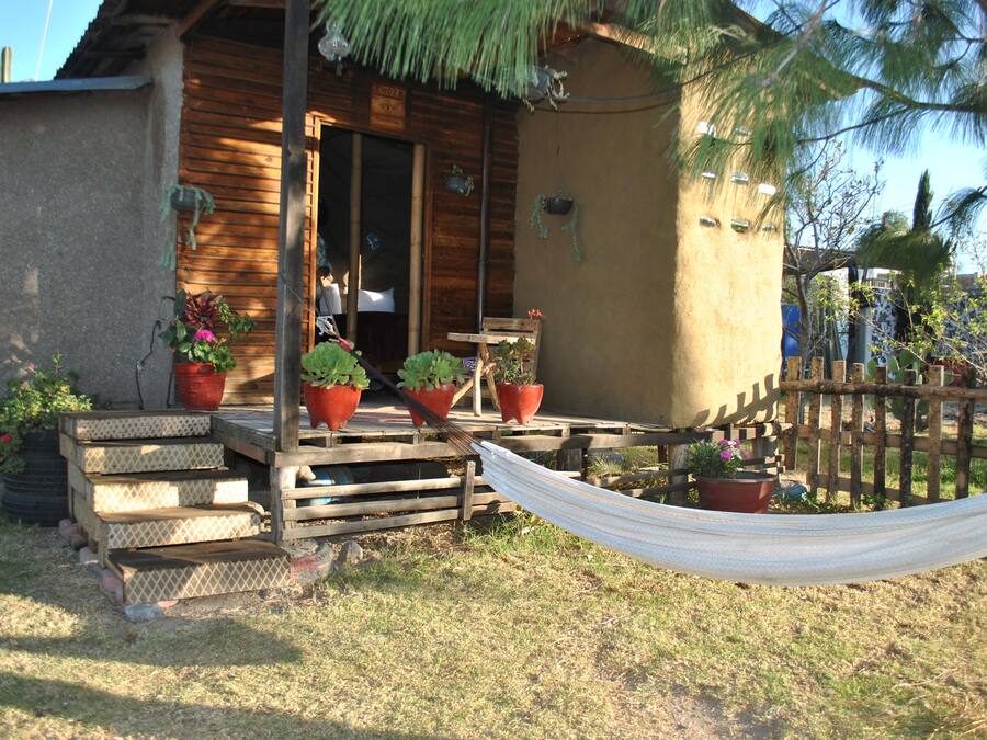 Uma cabana de madeira com varanda, degraus e uma rede.