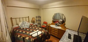Cozy retreat with a single bed, dresser, and comfortable seating area.