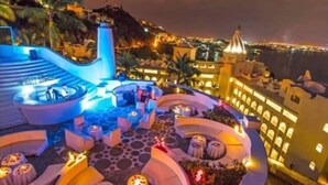Une terrasse sur le toit, avec des sièges en plein air et une vue sur la ville la nuit.