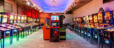 Una hilera de máquinas de arcade en una sala con suelo estampado y paredes de ladrillo.