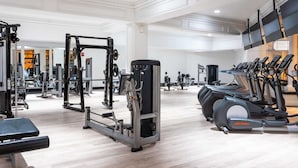 A spacious gym with various exercise equipment including weight machines, treadmills, and a bench. - Two Beachfront Stylish CozySuites  (Atlantic City)
