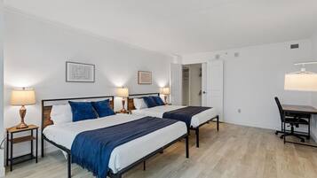 Un dormitorio con dos camas, un escritorio y una silla.