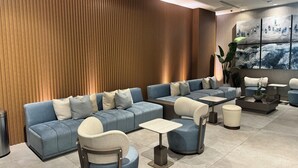 Un área de estar moderna con un sofá largo, un sillón redondo y una mesita.