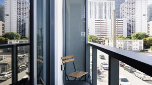 Un balcón con vista a un paisaje urbano, una puerta y dos sillas de madera.