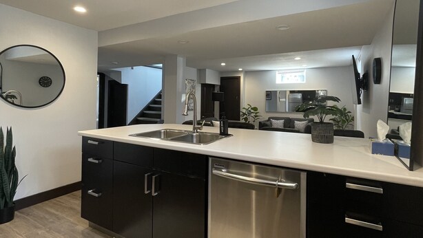 A modern kitchen with a large island, stainless steel appliances, and a large mirror. - The Lux Den Speaks for itself. Cozy, bright self-contained basement suite  (Yorkton)