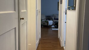 A hallway with wooden flooring leading to a bedroom with a bed and a nightstand. - 1 Bed Flat Sleeps 3 - Wifi, Near City Centre (London)