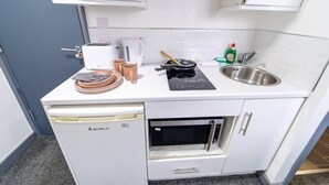 Une petite cuisine équipée comprenant un four encastré, une machine à café, une poêle et un évier.