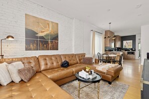 Una sala moderna con un sofá modular, una mesa de centro redonda y una gran obra de arte en la pared.