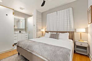 Un dormitorio con una cama grande, mesitas de noche, un espejo y un armario.