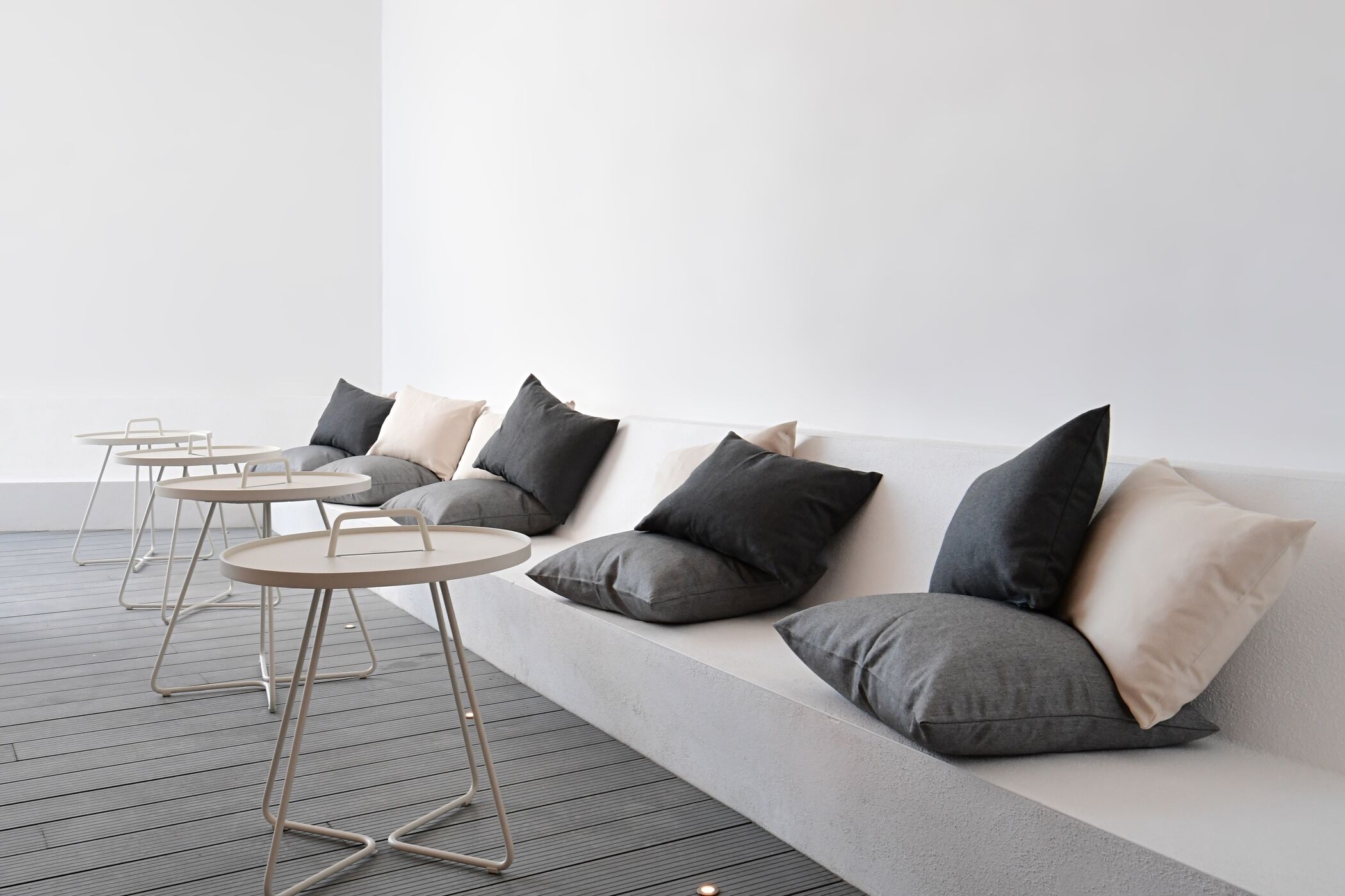 A modern seating area with a sofa and three round tables.