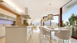 A modern kitchen with a central island, white bar stools, and a dining area with a view of the mountains. - Extraordinary 7 BDRM Villa w Pool, Gym, Cinema (Marbella)