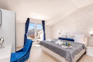 A modern bedroom with a bed, a chair, a bedside table, and a view of the outdoors.