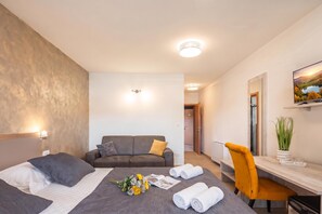 Habitación de hotel con cama, sofá, escritorio y televisor.