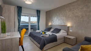 Una habitación de hotel moderna con una cama, mesitas de noche, un escritorio y vistas al exterior.