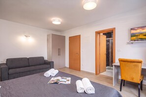 Une chambre d’hôtel moderne, équipée d’un lit, d’un canapé, d’un bureau et d’un tableau au mur.