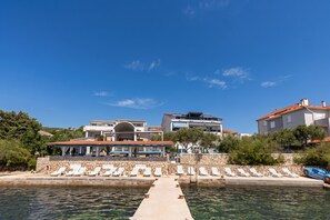 Una proprietà sul lungomare con piscina, lettini e un muro in pietra.