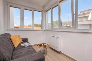 Un soggiorno moderno con un divano grigio, un piccolo tavolino in legno e un termosifone bianco.