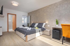Un dormitorio moderno con cama, mesita de noche y escritorio con silla.