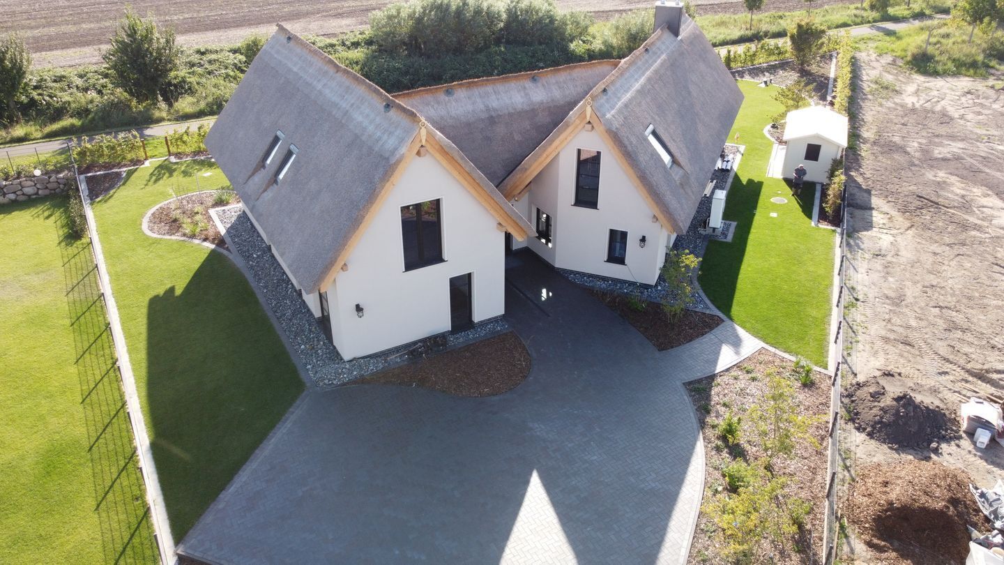 A modern house with two attached sections, each with a gabled roof and white exterior.