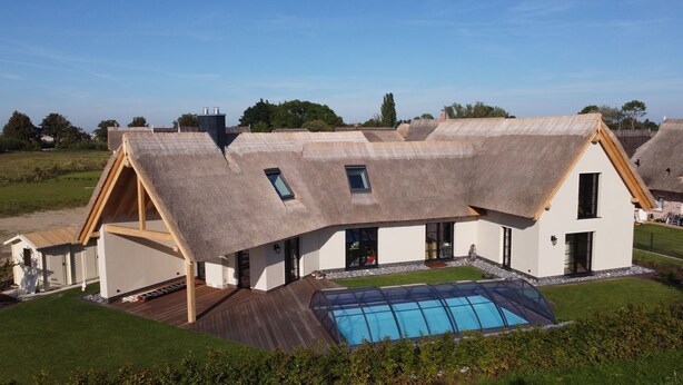 A modern house with a sloped roof, a swimming pool, and a well-maintained lawn. - Ferienhaus Inselglück in der Puddeminer Wiek (Poseritz)