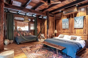 Una habitación rústica de madera con una cama, un banco y una hamaca.