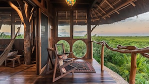 Un interior de madera con una hamaca, un sillón mecedor y vistas al exterior.