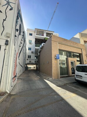Une vue de rue avec un immeuble en construction, un fourgon blanc garé et un panneau de signalisation de stationnement bleu.