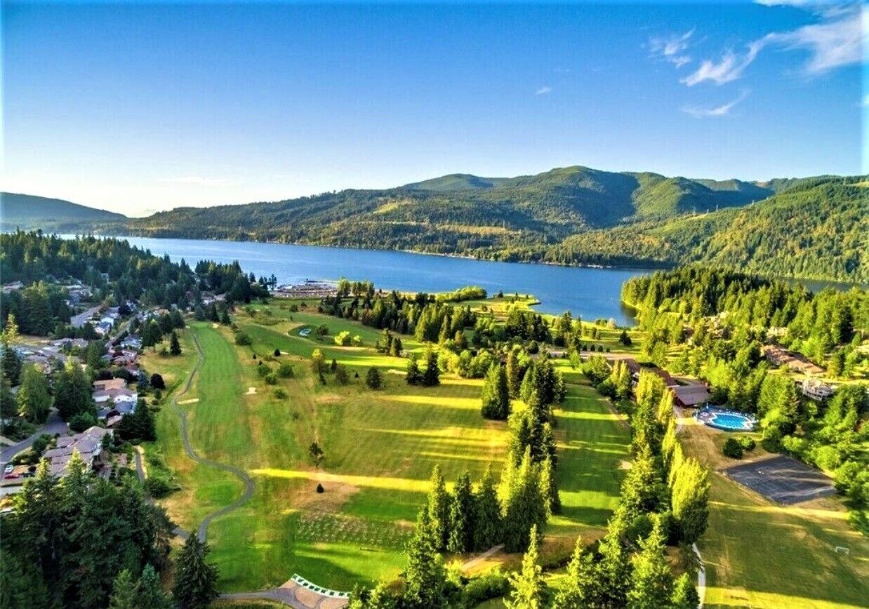 Eine Luftaufnahme eines Golfplatzes mit einem See, umgeben von Hügeln und dichten Wäldern.