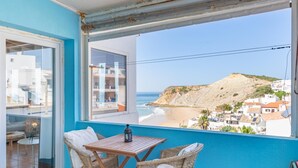 Un balcon doté de meubles en osier et offrant une vue sur la plage et les bâtiments.