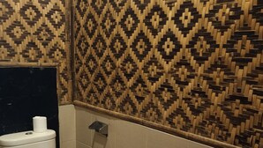 A bathroom with a patterned wall, a toilet, and a tiled floor.