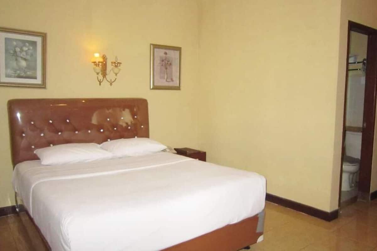A neatly made bed with white linens in a hotel room.