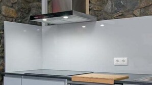 Een keuken met een stenen muur, een roestvrijstalen afzuigkap en een inbouwkoelkast.