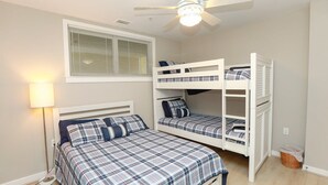 Un dormitorio con una cama individual, una litera, un ventilador de techo y una ventana con persianas.