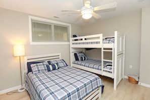 Un dormitorio con una cama individual, una litera, un ventilador de techo y una ventana con persianas.