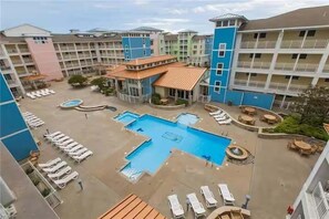 Un hotel con varias construcciones, piscina central y zonas de estar al aire libre.