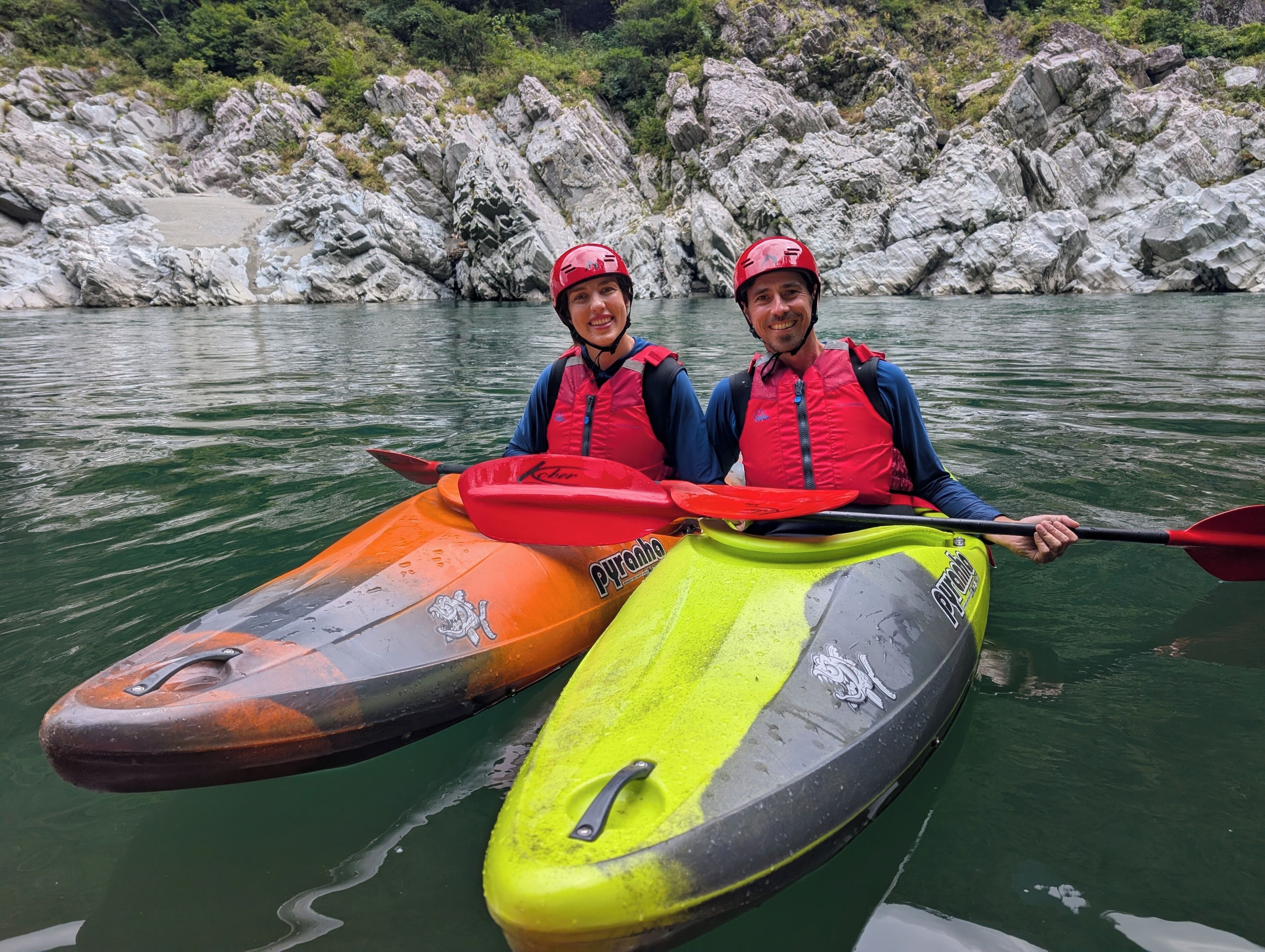 Dos kayaks sobre aguas tranquilas, con terreno rocoso al fondo.
