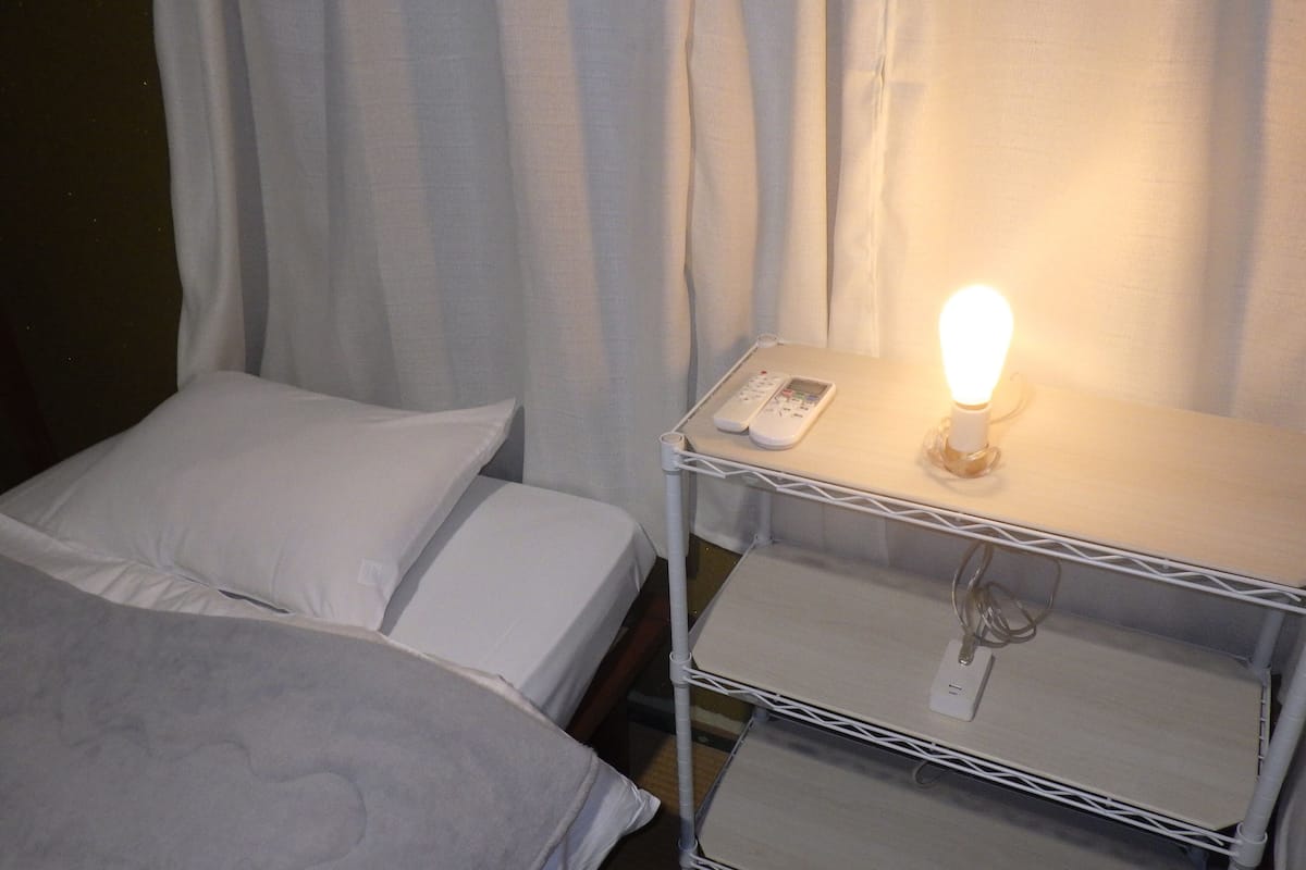 A hotel room with two beds, a bedside table with a lamp, and a charging station.
