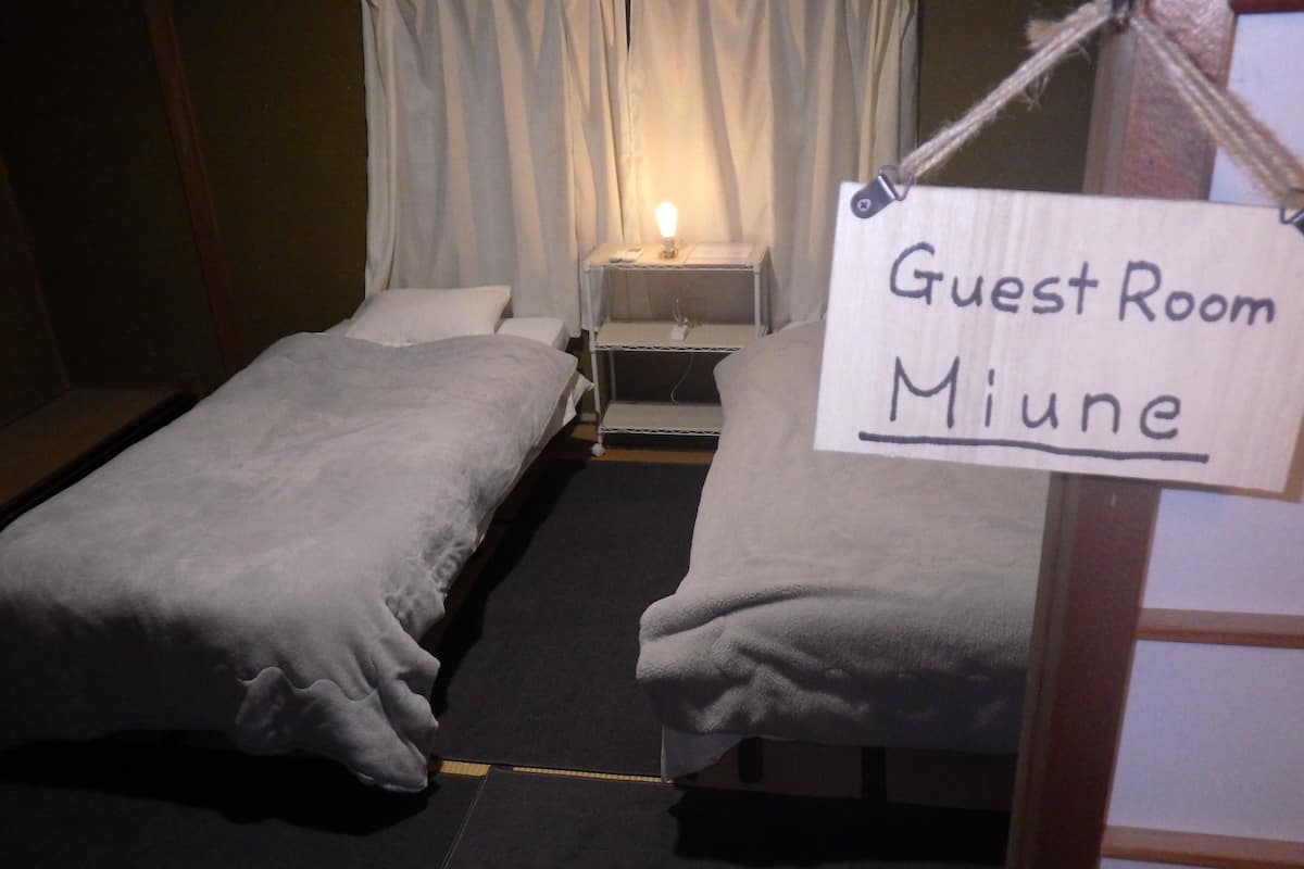 A guest room with two beds, a nightstand, and a sign indicating it is the guest room of Miune.
