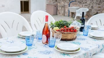 A table set for a meal with plates, glasses, a bottle, and a basket of fresh vegetables.