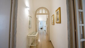 A hallway with white walls, framed pictures, and a glass display table.