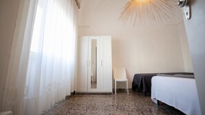 A hotel room with a bed, a chair, a wardrobe, and a unique ceiling light fixture.