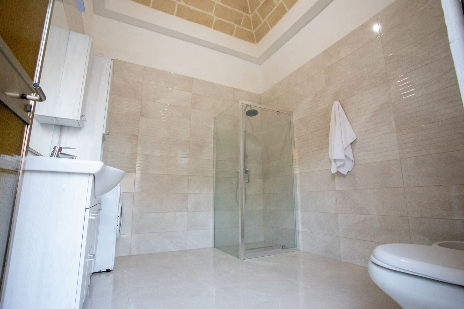 A modern bathroom with a glass-enclosed shower, a white sink, and a toilet.