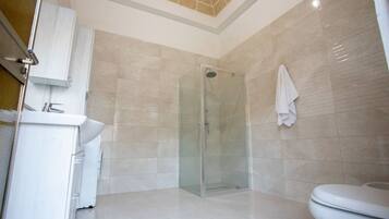 A modern bathroom with a glass-enclosed shower, a white sink, and a toilet.