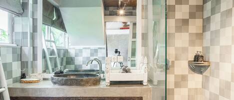 A bathroom with a large mirror, a sink, and a shower area.