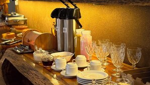 A breakfast buffet setup with a variety of food items and beverages, a coffee maker, and a wicker headboard in the background. - POUSADA ALTER PARA TODOS (Santarem)