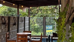 An outdoor seating area with wooden tables and chairs, a thatched roof, and string lights. - POUSADA ALTER PARA TODOS (Santarem)