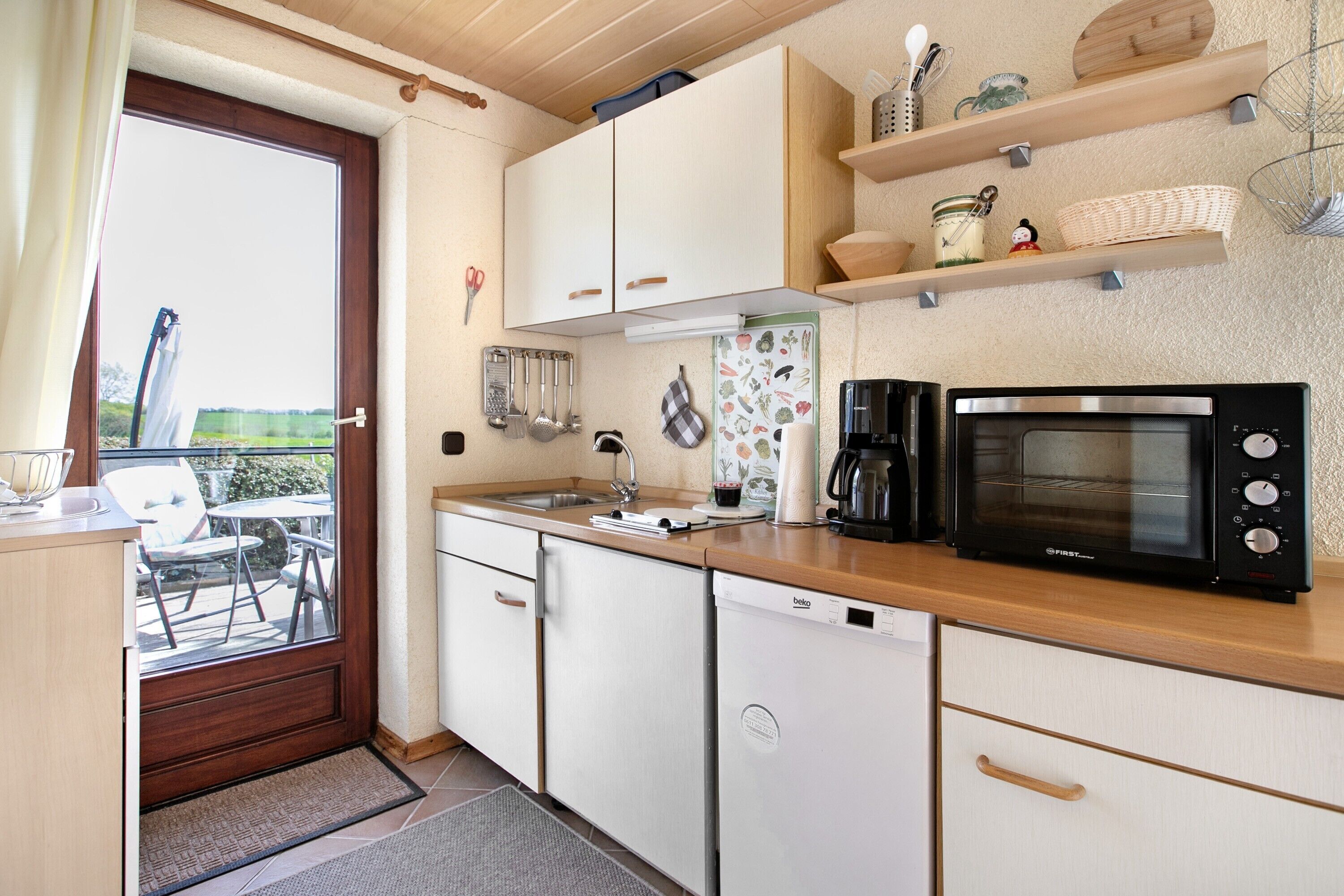 Una cocina compacta equipada con lavavajillas, microondas y ventana con vistas a un patio.