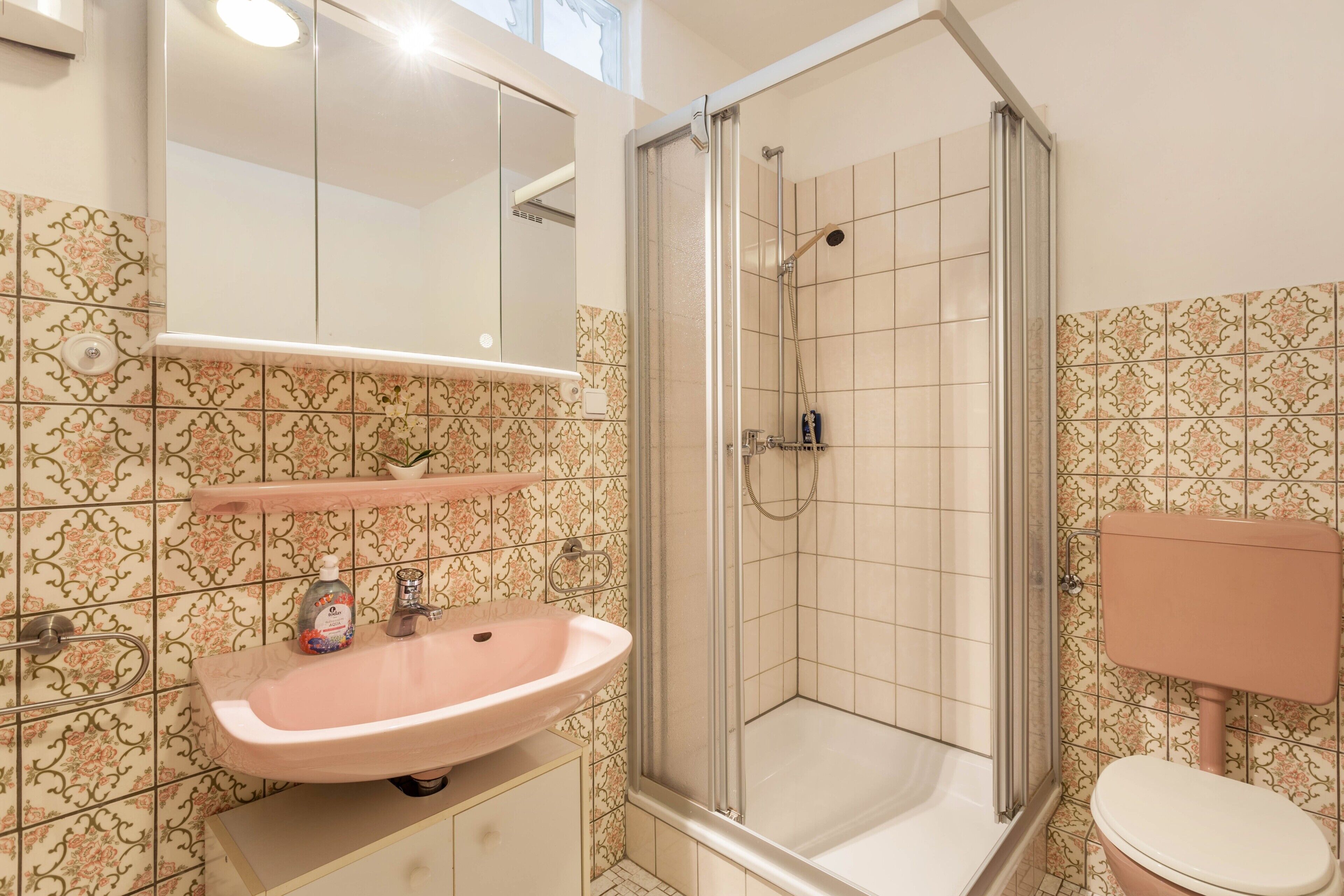 A bathroom with a shower, sink, toilet, and a mirror.